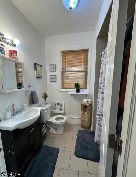 bathroom with toilet, tile patterned flooring, vanity, and a baseboard radiator