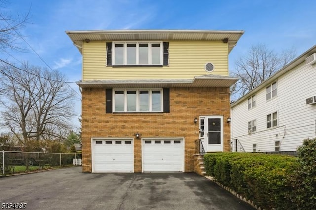 view of front facade with driveway, an attached garage, brick siding, and fence