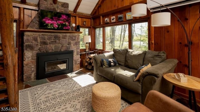 living area with wooden walls, a fireplace, and vaulted ceiling