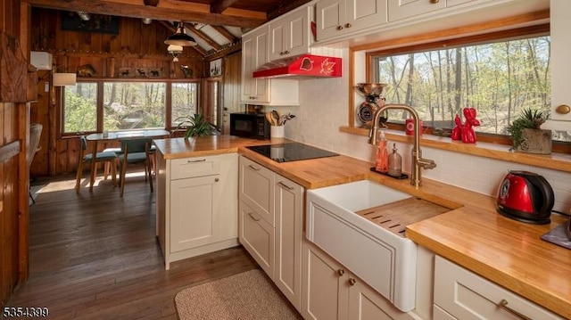 kitchen with butcher block countertops, white cabinetry, black appliances, and tasteful backsplash