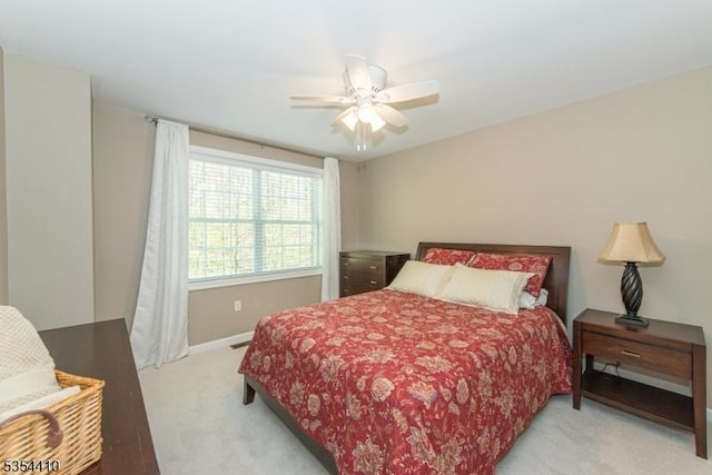 bedroom with a ceiling fan, baseboards, and light colored carpet