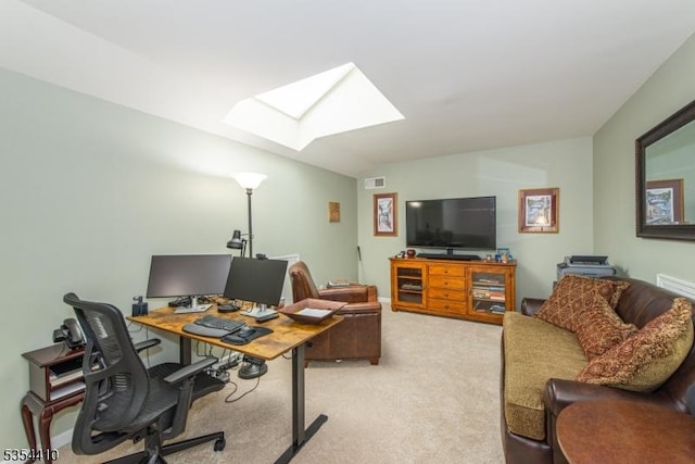 office with light colored carpet, visible vents, and vaulted ceiling with skylight