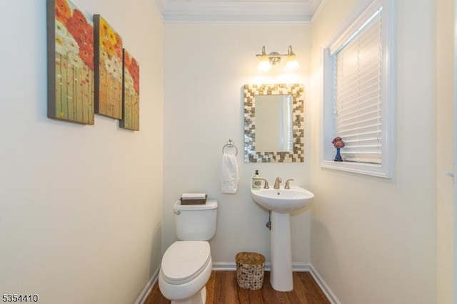 half bathroom with baseboards, ornamental molding, toilet, and wood finished floors