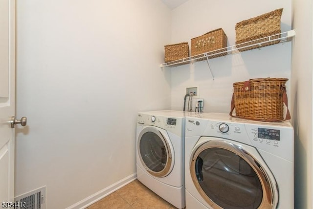 clothes washing area with laundry area, baseboards, light tile patterned floors, visible vents, and washer and clothes dryer