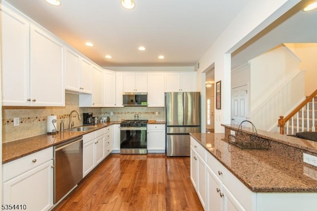 kitchen featuring appliances with stainless steel finishes, a sink, white cabinetry, recessed lighting, and decorative backsplash