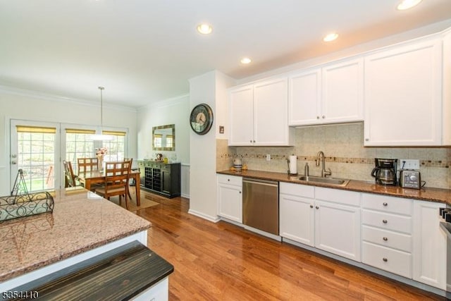 kitchen featuring stainless steel dishwasher, a sink, decorative backsplash, and crown molding