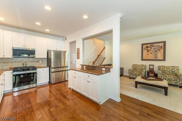 kitchen with backsplash, stainless steel appliances, and white cabinetry