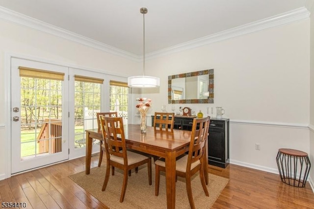 dining area featuring crown molding, baseboards, plenty of natural light, and wood finished floors