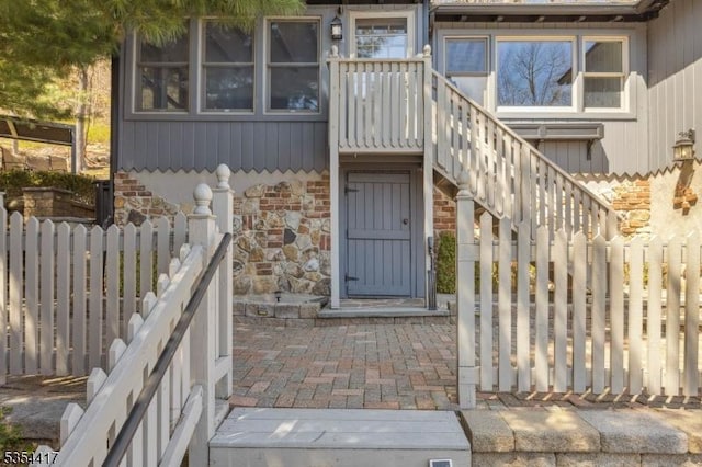 entrance to property featuring fence and stone siding