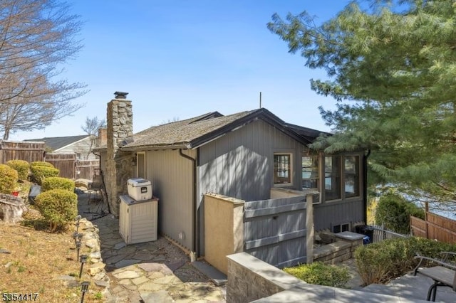 view of side of property with fence and a chimney