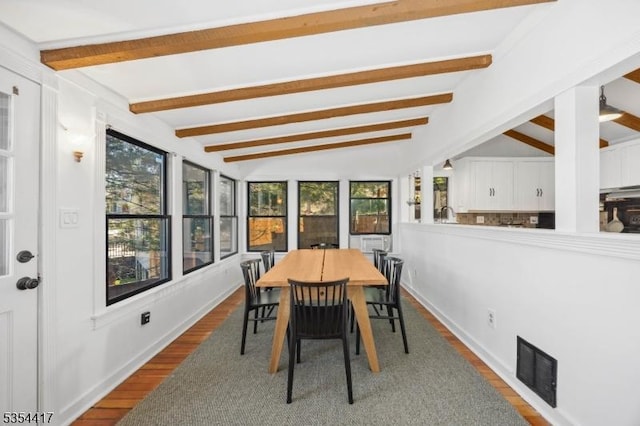 dining space featuring visible vents, lofted ceiling with beams, dark wood-style flooring, and a wealth of natural light