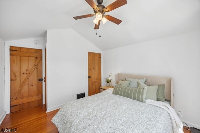 bedroom featuring visible vents, wood finished floors, baseboards, ceiling fan, and vaulted ceiling