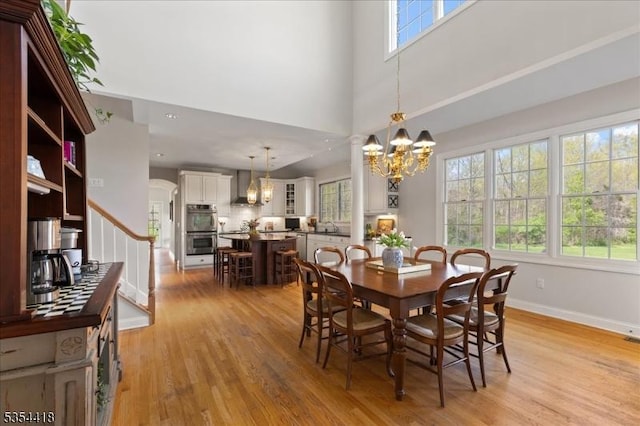 17 Hunters Path, Montgomery Twp, NJ 08558 - dining space featuring a chandelier, baseboards, light wood-type flooring, a towering ceiling, and stairway