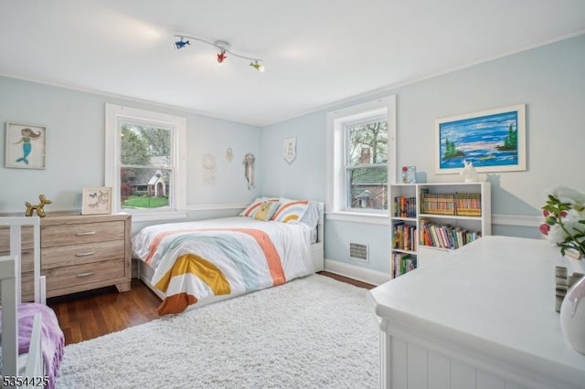 bedroom featuring visible vents, rail lighting, and dark wood finished floors