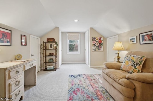 living area with baseboards, light colored carpet, and lofted ceiling