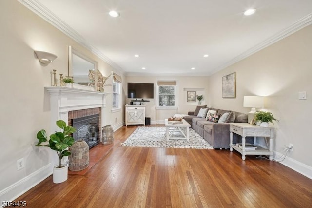 living room featuring crown molding, a fireplace, wood finished floors, baseboards, and recessed lighting