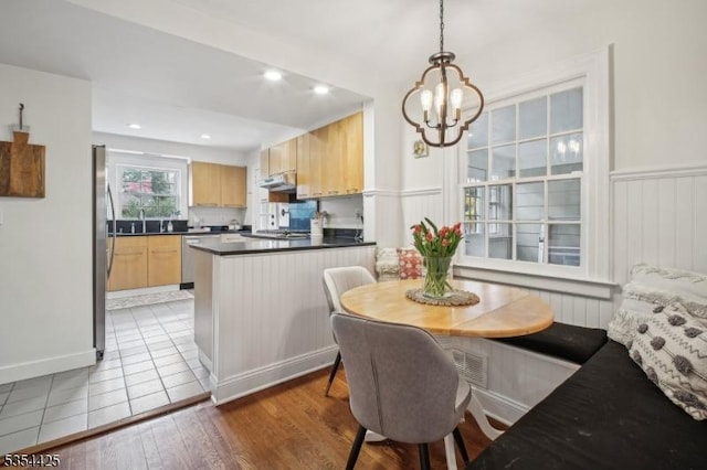 dining space featuring an inviting chandelier, recessed lighting, light wood finished floors, and a wainscoted wall