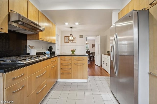 kitchen with dark countertops, appliances with stainless steel finishes, hanging light fixtures, a peninsula, and under cabinet range hood