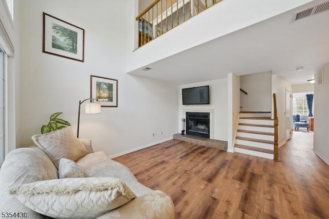 living room with visible vents, stairs, wood finished floors, and a tile fireplace