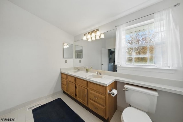 bathroom featuring double vanity, toilet, visible vents, and a sink