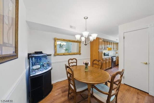 dining space featuring a chandelier, wood finished floors, and visible vents