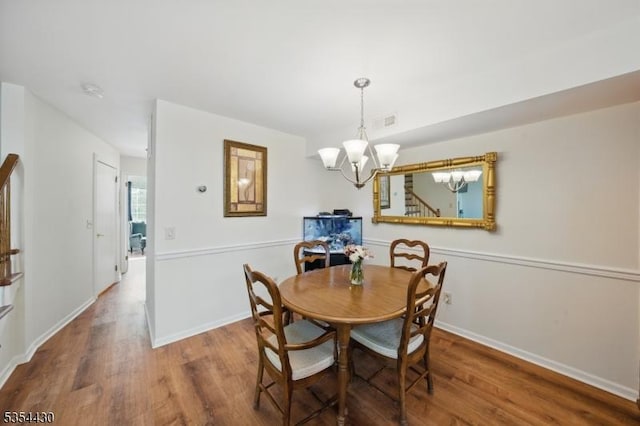 dining space with baseboards, wood finished floors, and a notable chandelier