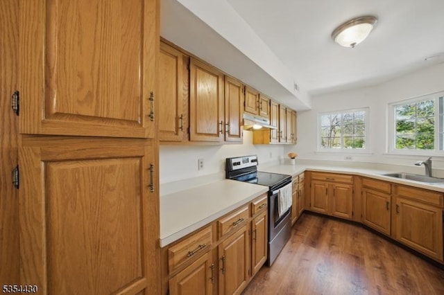 kitchen featuring electric range, a sink, light countertops, under cabinet range hood, and dark wood-type flooring