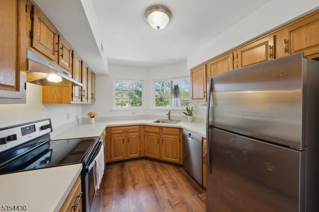 kitchen featuring under cabinet range hood, appliances with stainless steel finishes, dark wood-type flooring, and light countertops
