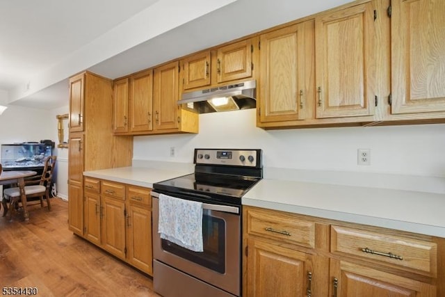 kitchen featuring light countertops, stainless steel electric range, under cabinet range hood, and light wood-style flooring