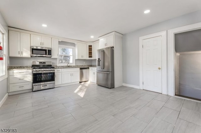 kitchen with light stone counters, white cabinets, baseboards, and stainless steel appliances