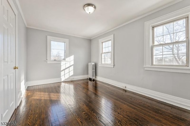 spare room with baseboards, ornamental molding, dark wood-style flooring, and radiator heating unit