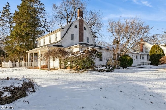 view of snow covered exterior with a porch and a chimney