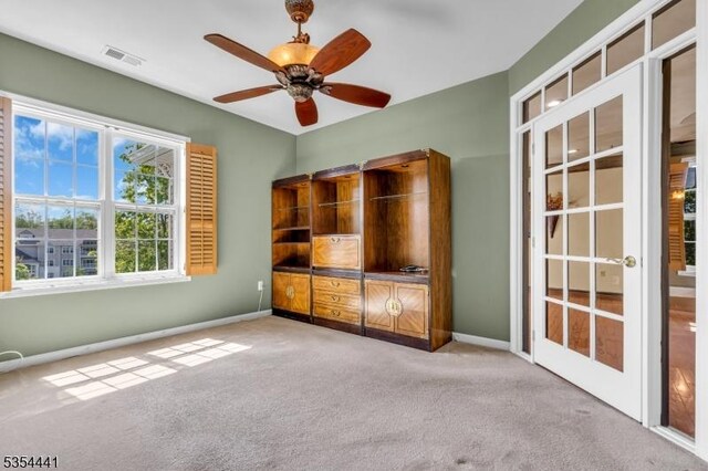 unfurnished living room featuring carpet floors, baseboards, and ceiling fan