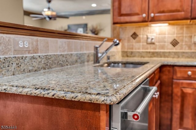 kitchen featuring a sink, tasteful backsplash, light stone countertops, and dishwasher
