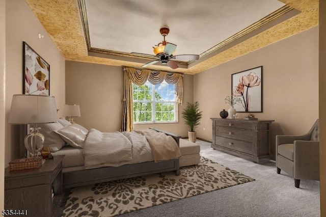 bedroom with a raised ceiling, carpet floors, ceiling fan, and ornamental molding