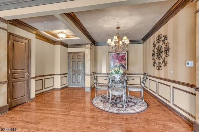 dining space featuring a decorative wall, crown molding, a chandelier, wood finished floors, and coffered ceiling