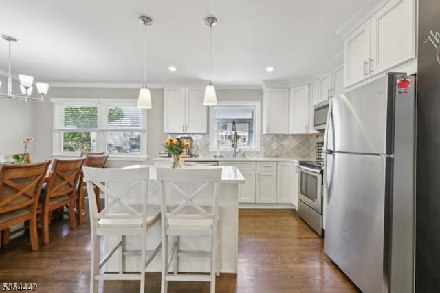 kitchen with light countertops, appliances with stainless steel finishes, crown molding, and white cabinetry