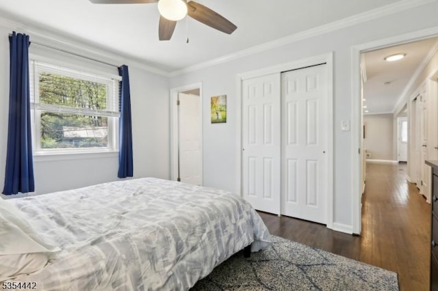 bedroom featuring a ceiling fan, dark wood-style flooring, crown molding, baseboards, and a closet