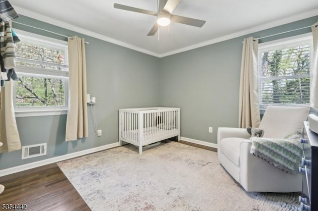 bedroom featuring baseboards, visible vents, ornamental molding, and wood finished floors