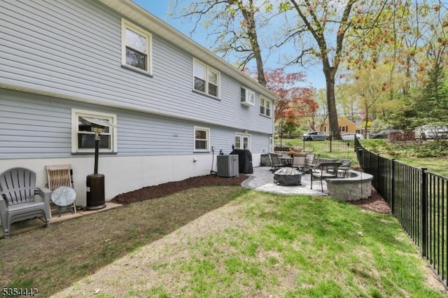 back of property featuring a fire pit, cooling unit, a patio, a fenced backyard, and a lawn