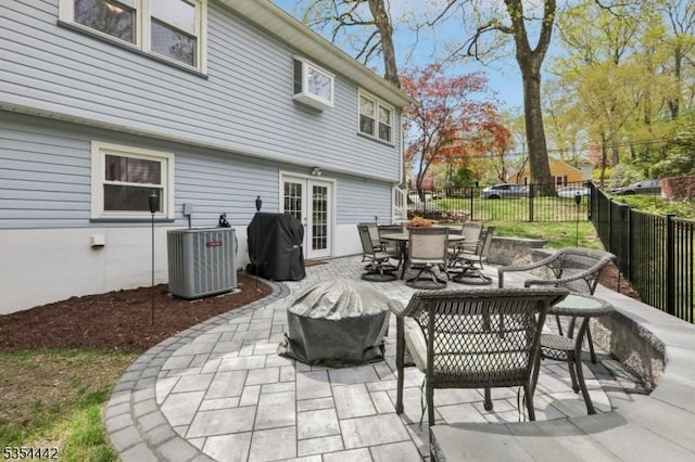 view of patio featuring fence, outdoor dining area, central AC, and french doors
