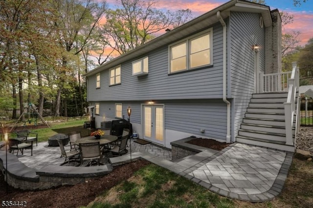 back of property at dusk with french doors and a patio area