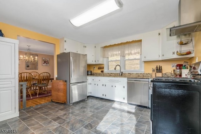 kitchen with stainless steel appliances, wall chimney range hood, white cabinets, a chandelier, and light stone countertops