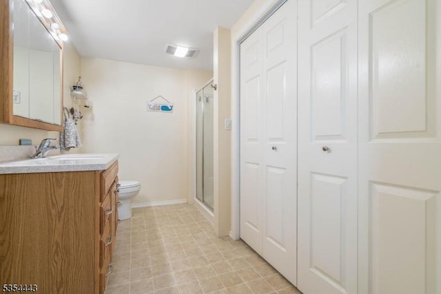bathroom with toilet, baseboards, vanity, a stall shower, and a closet