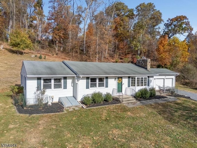 ranch-style house featuring a front lawn, an attached garage, a chimney, and roof with shingles