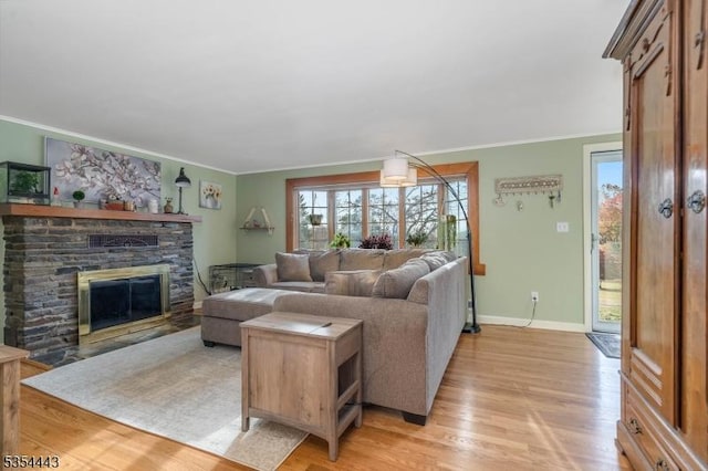 living room featuring crown molding, a fireplace, light wood finished floors, and baseboards