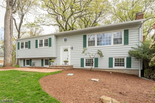 bi-level home featuring a chimney and a front yard