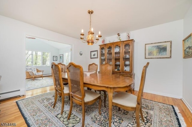 dining area with a baseboard heating unit, vaulted ceiling, a chandelier, and light wood finished floors