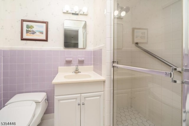 bathroom featuring vanity, wainscoting, toilet, tile walls, and a shower stall