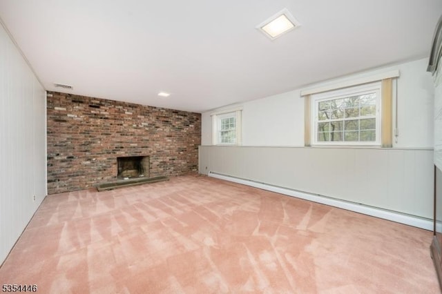 unfurnished living room with visible vents, carpet, a brick fireplace, and a baseboard heating unit